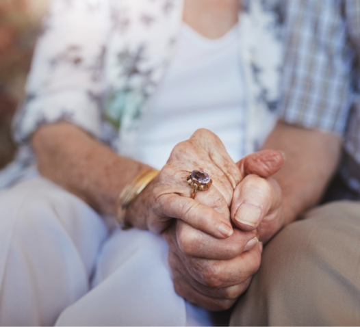 Äldre personer som håller varandras händer, en med en ring.