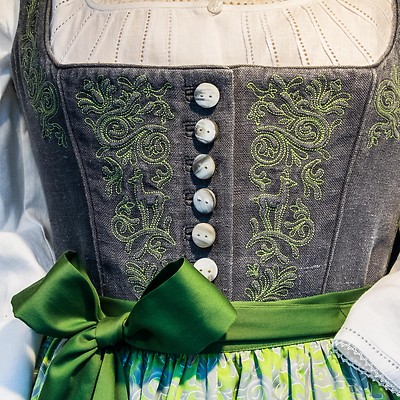 Traditionell klänning med broderat livstycke och grön rosett i midjan.