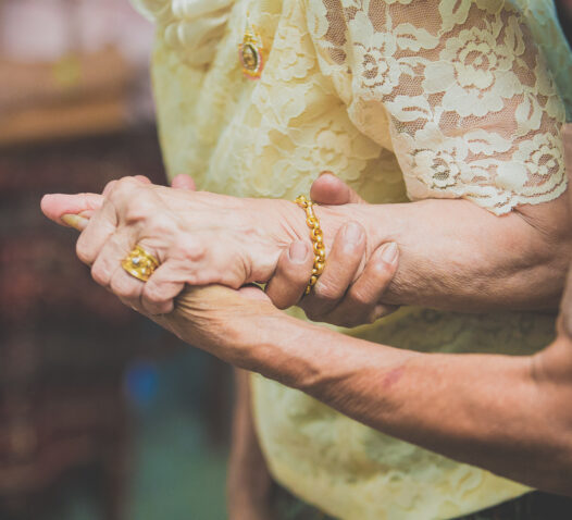 Två äldre personer håller varandra i händerna, klädda i gul spets.