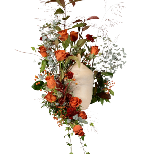 En beige urna omgiven av orange rosor, gröna blad och vita blommor mot svart bakgrund.